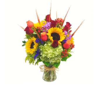 Bouquet of sunflowers, roses, hydrangea, and mixed blooms in a glass vase