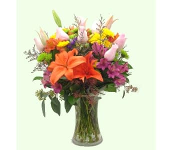 Mixed bouquet of lilies and colorful flowers in a clear glass vase
