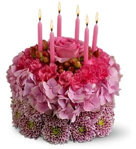 Pink floral cake with lit pink candles on top