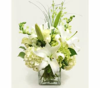 White lilies and pale green hydrangeas in a clear glass vase