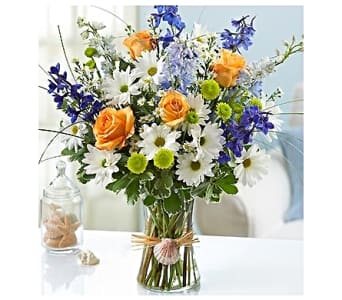 Bouquet of orange roses, white daisies, and blue flowers in a glass vase