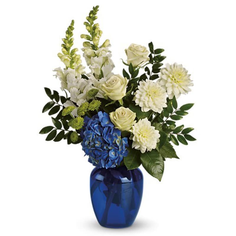 White and blue floral arrangement in a cobalt vase