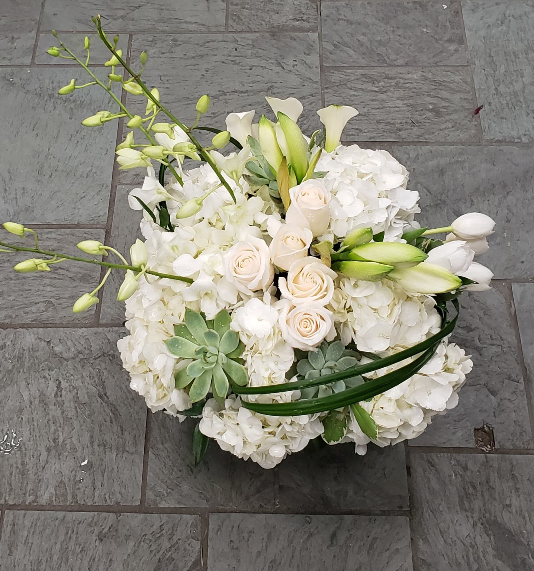White floral arrangement with roses, orchids, and calla lilies