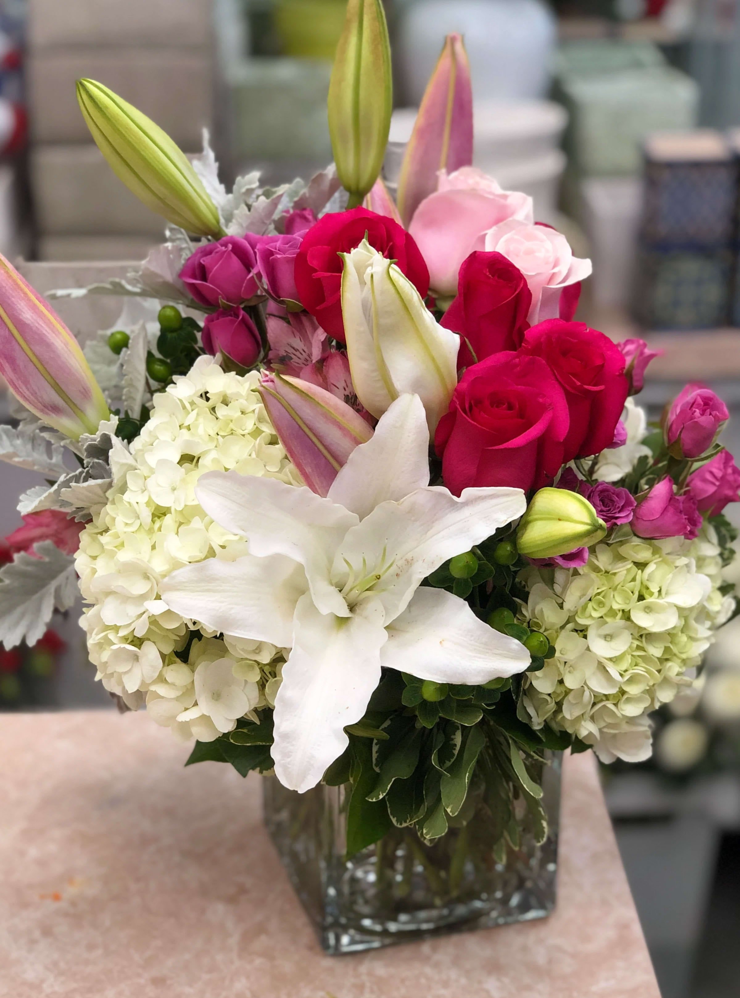 Bouquet of pink and white roses, lilies, and hydrangeas in a glass vase