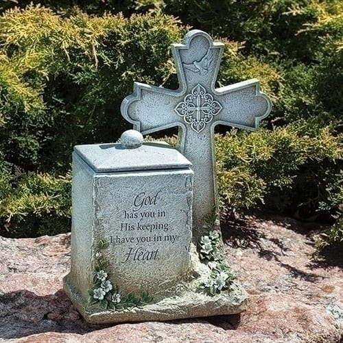 Stone memorial urn and cross with engraved message in a garden setting