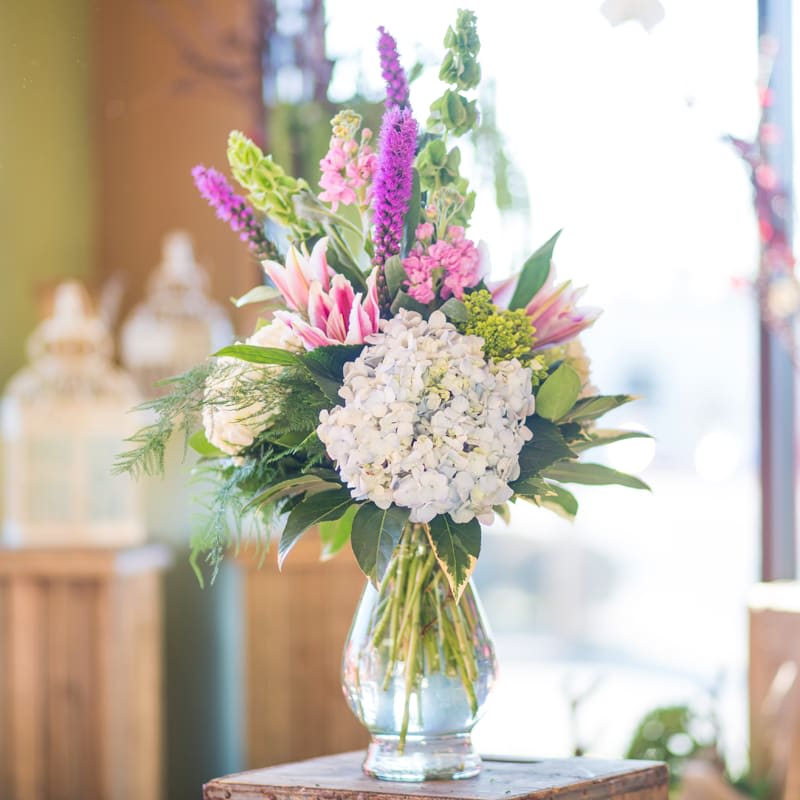 Bouquet of white hydrangeas and pink-purple flowers in a glass vase