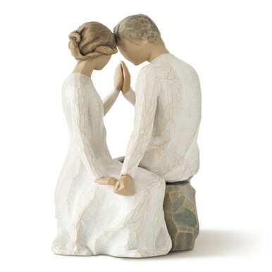 A carved figurine of a seated couple touching foreheads and hands.