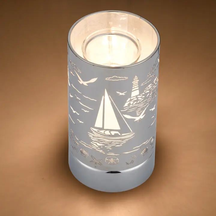 White candle in a silver holder with sailboat and lighthouse cutout design