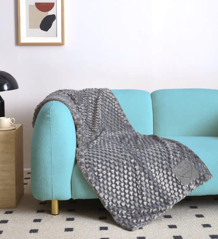 Gray textured throw blanket draped over a turquoise sofa