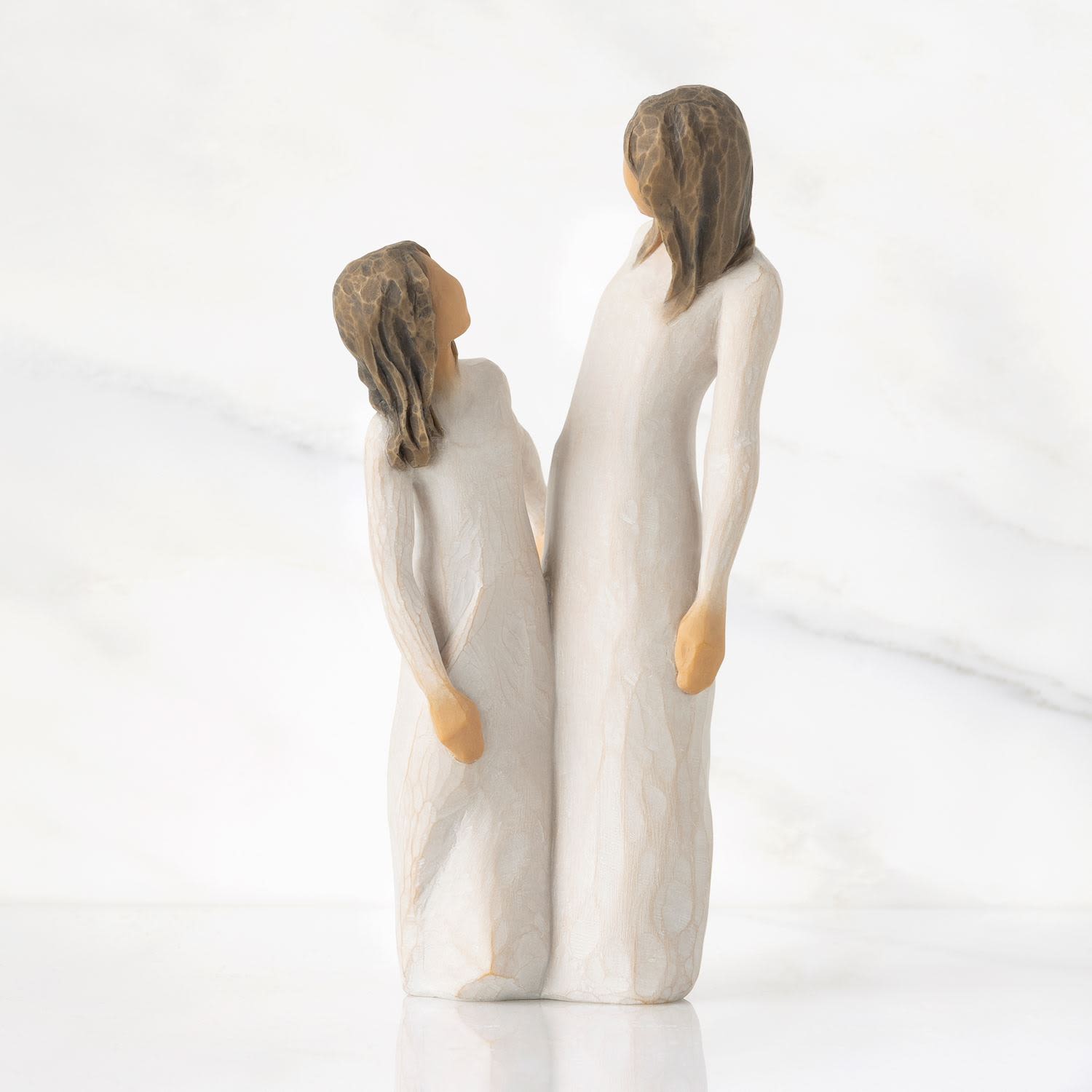 Two carved figurines of a woman and child in white robes