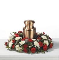 Red and white floral wreath around a bronze urn