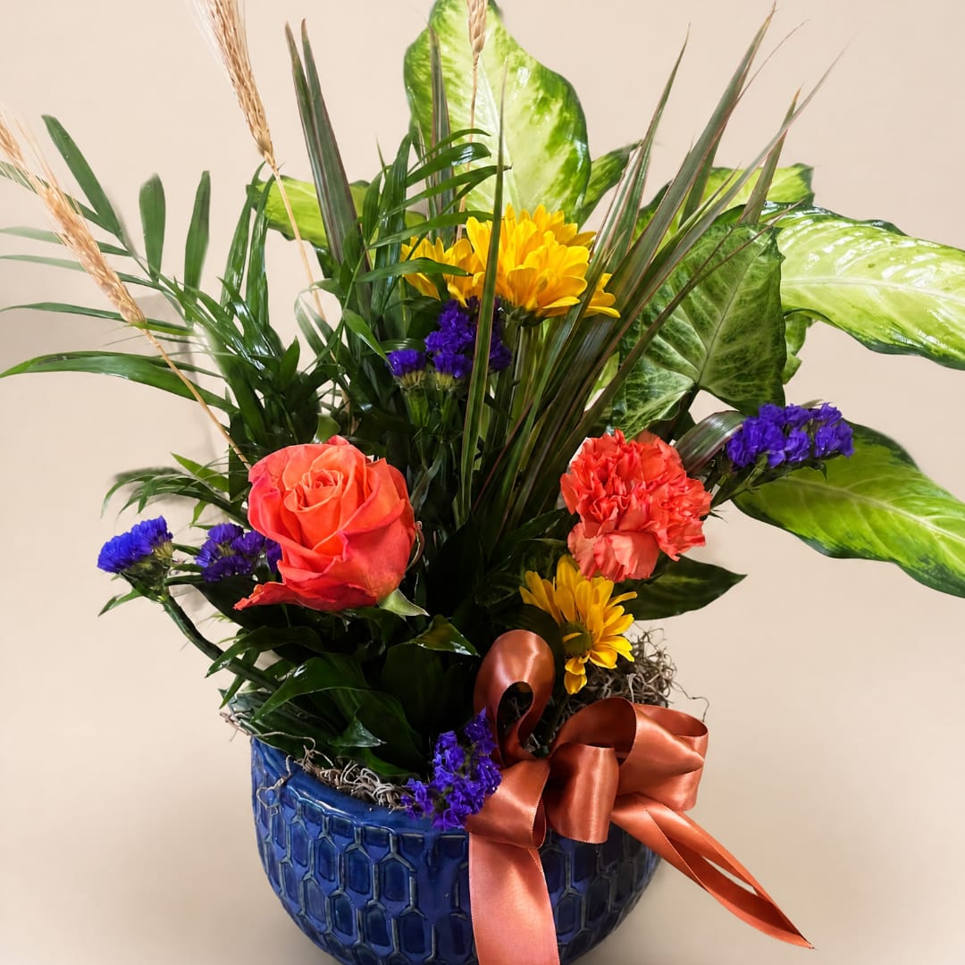 Colorful floral arrangement in a blue ceramic vase with a satin ribbon