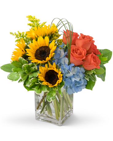 Bouquet of sunflowers, blue hydrangeas, and coral roses in a glass vase