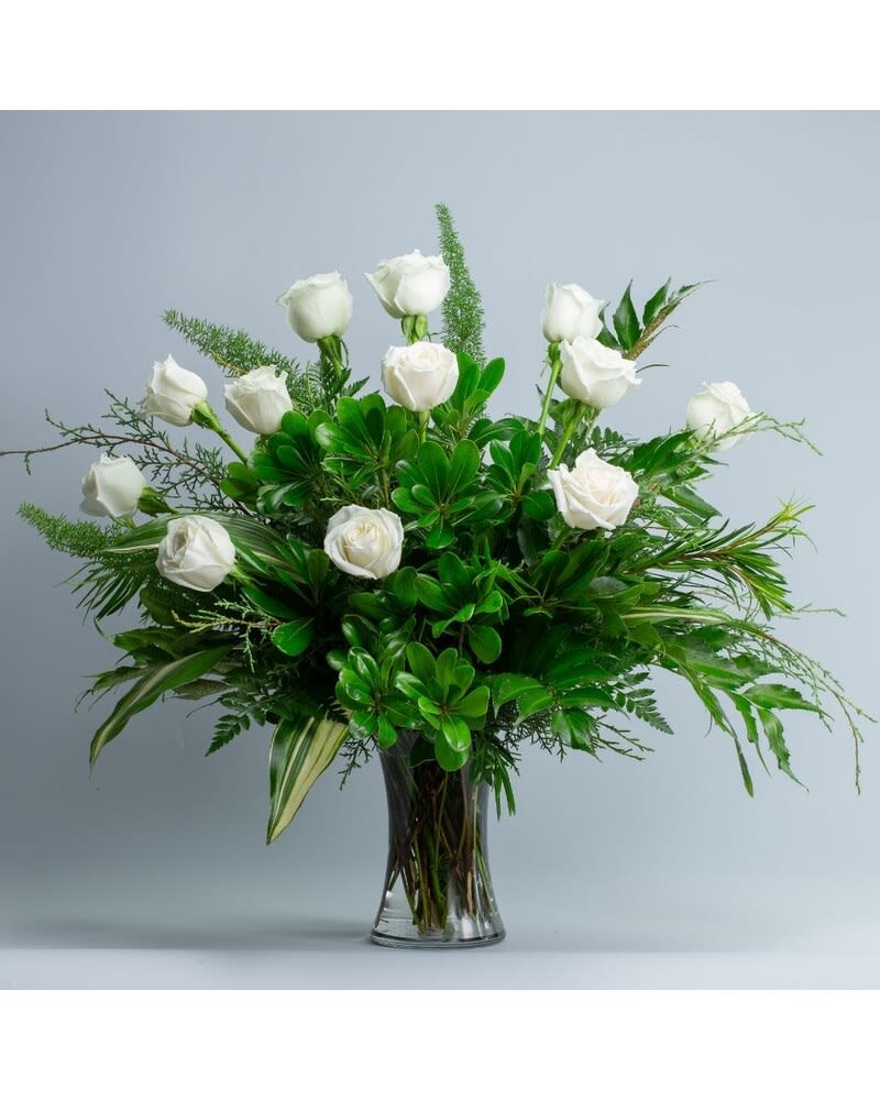 Pearls - Elegance at its best. Pearls will add sophistication. These pearly white roses are accented with a graceful mixture of foliage in a tall clear glass flared vase appropriate for an entry table. Approximately 30" W X 27" H The container for this arrangement may vary, based on availability.  