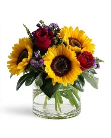 Sunflowers and red roses arranged in a clear glass vase