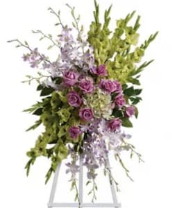 Tall floral spray with purple roses and green blooms on a white stand
