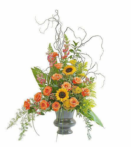 Orange roses and sunflowers in a gray vase with curly branches
