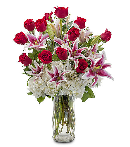 Bouquet of red roses and pink lilies in a clear glass vase