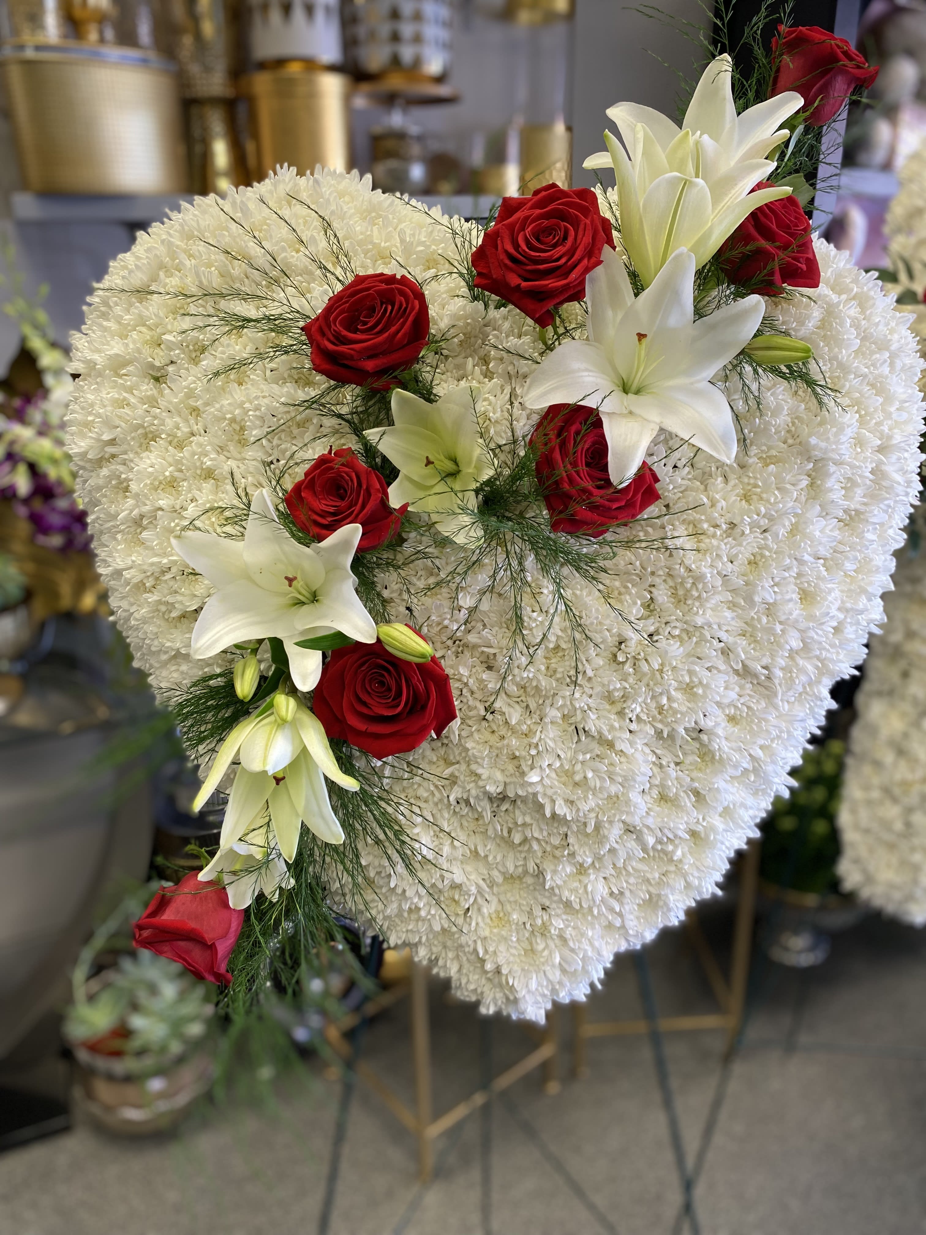 Heart-shaped white floral arrangement with red roses and white lilies
