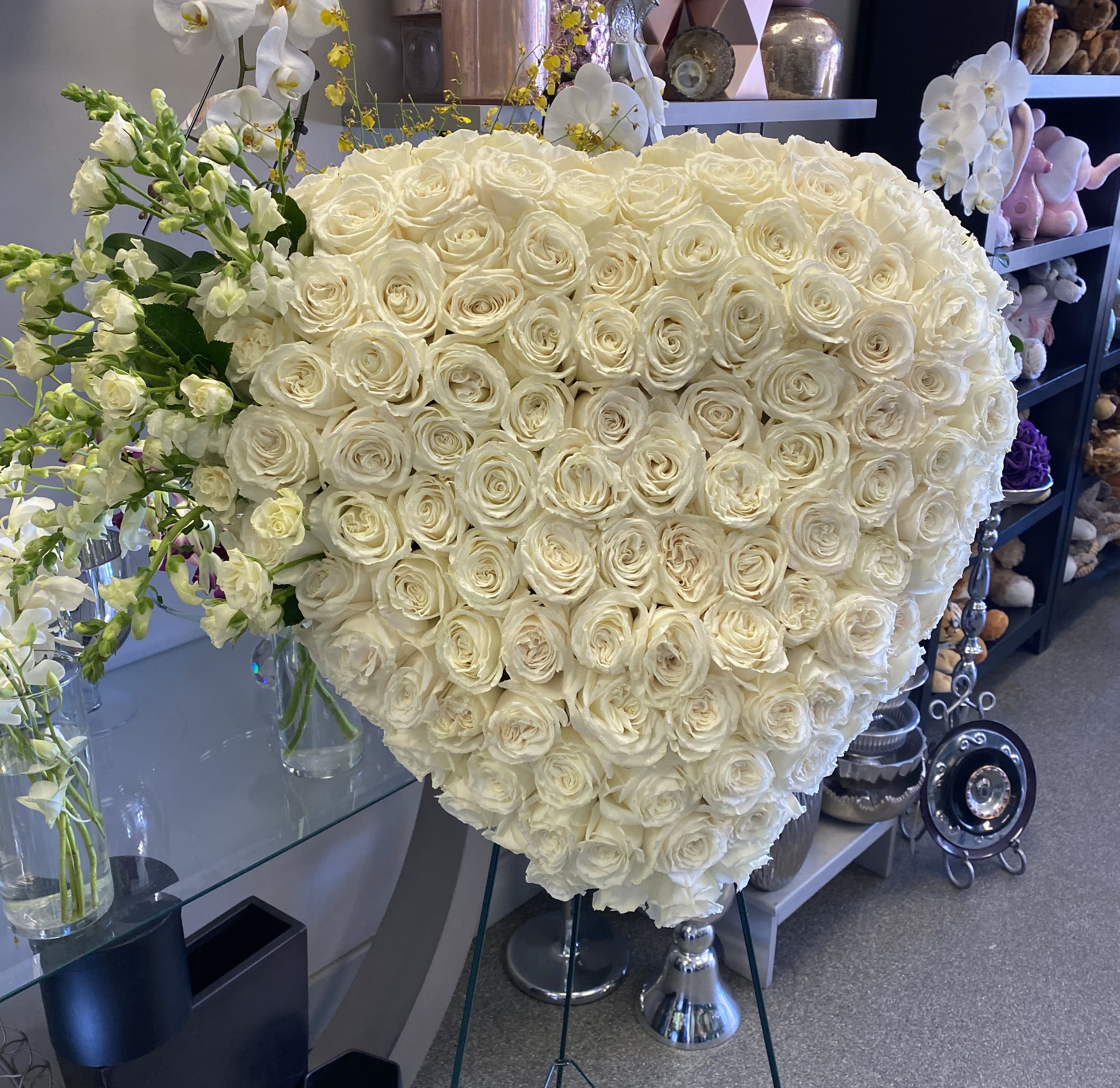 Large heart-shaped arrangement of white roses with white orchids