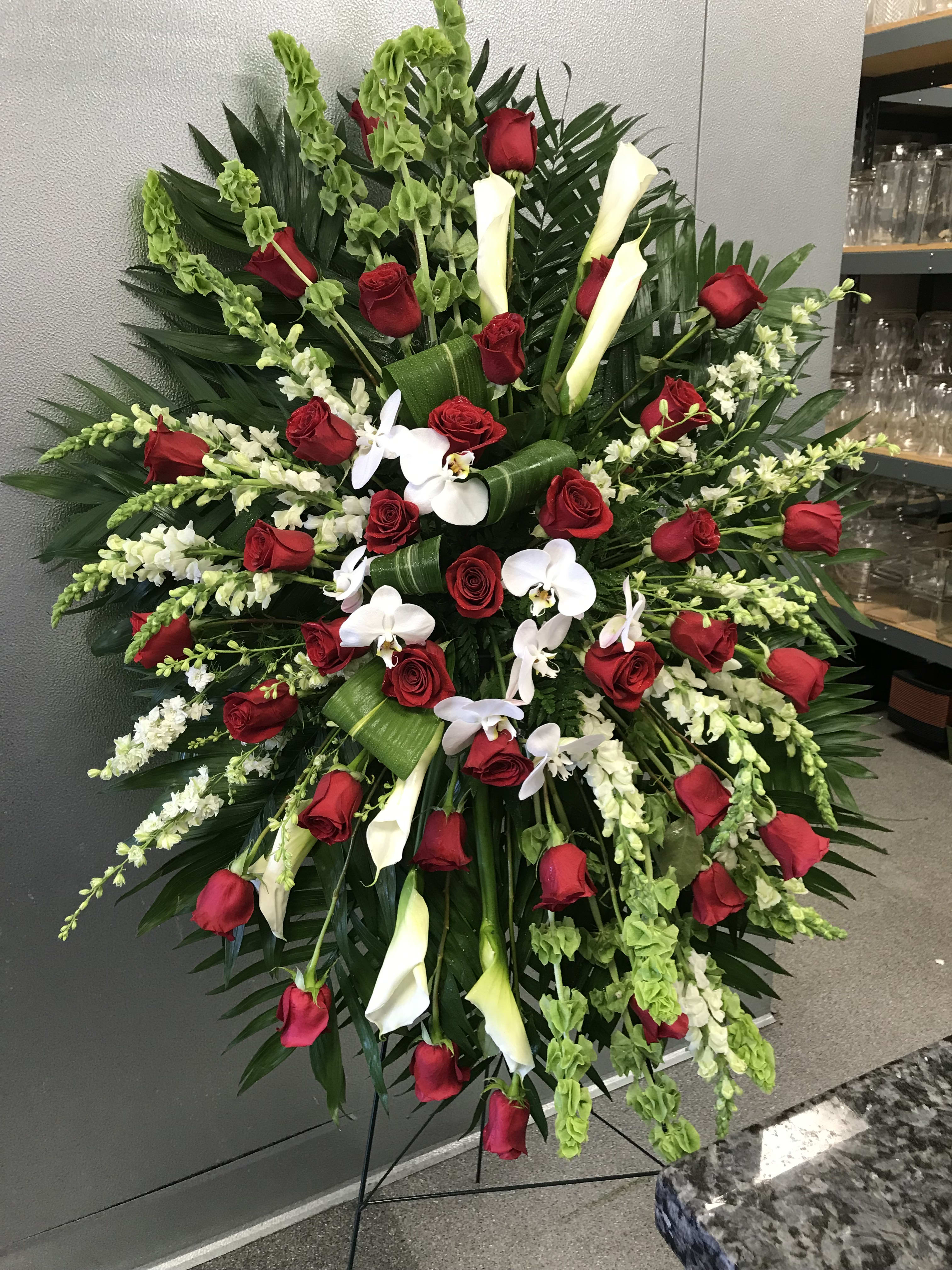 Large standing floral spray with red roses, white calla lilies, and white orchids