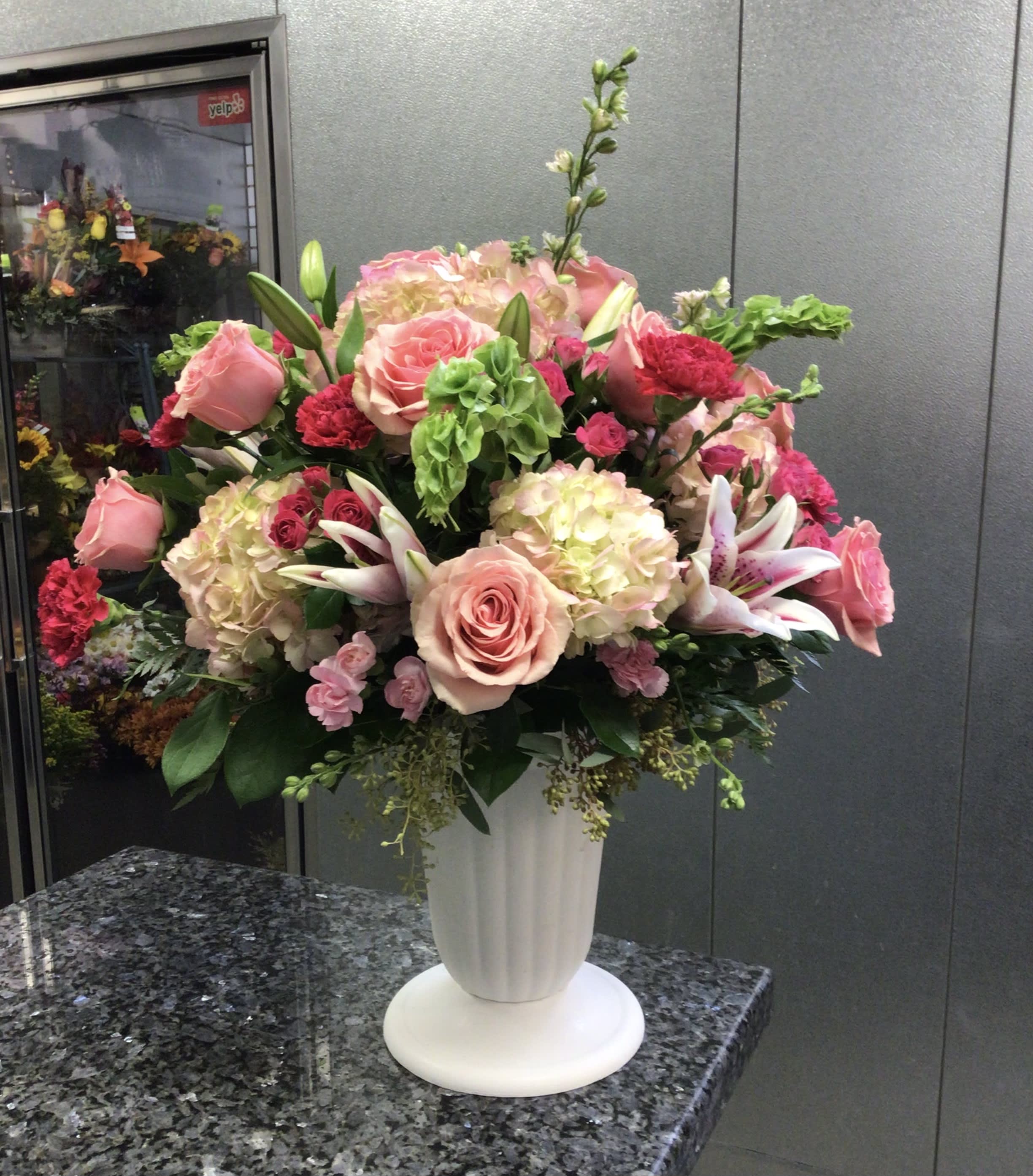 Large pink and white floral arrangement in a white vase