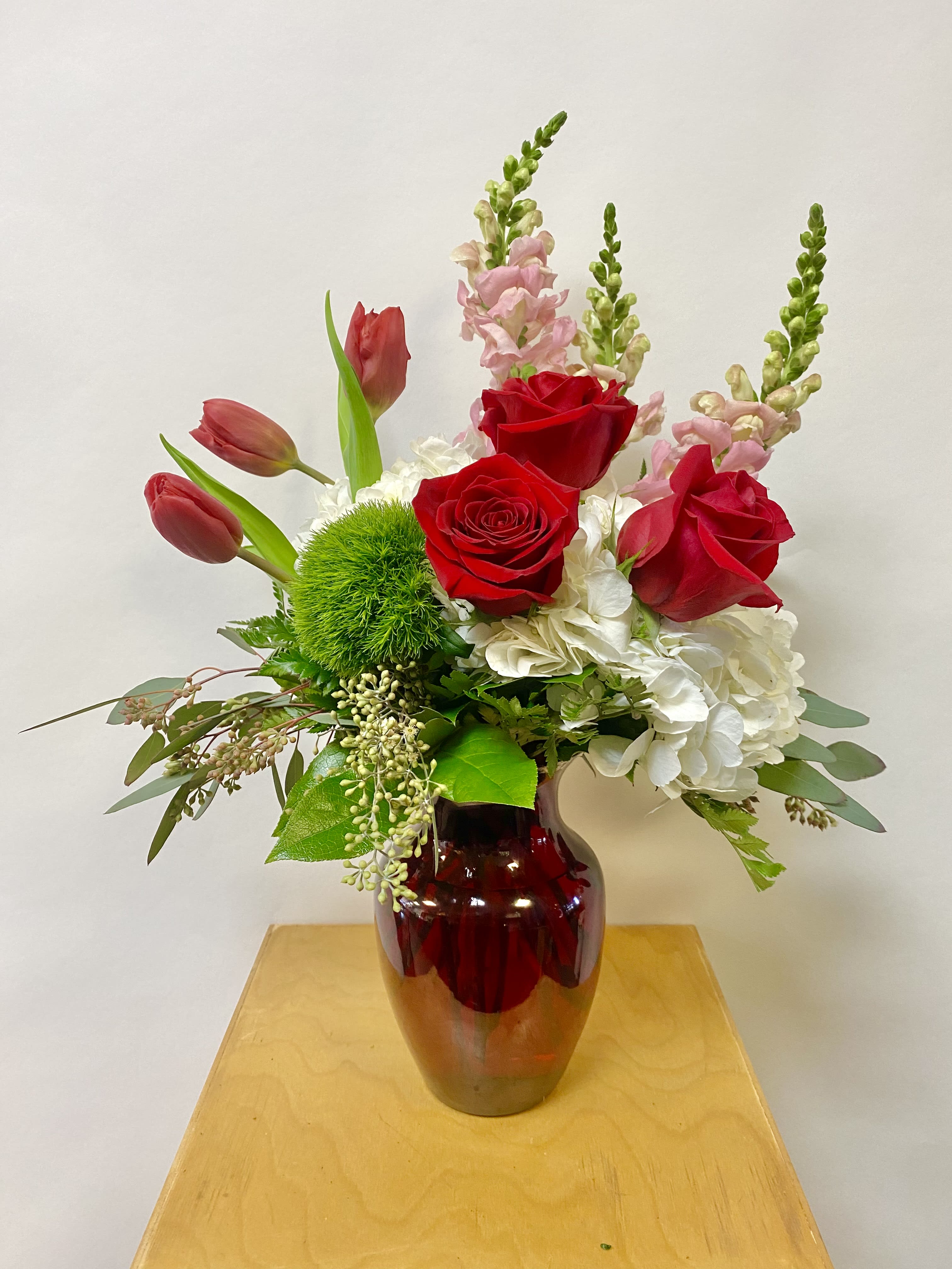 Red roses and pink tulips in a red glass vase