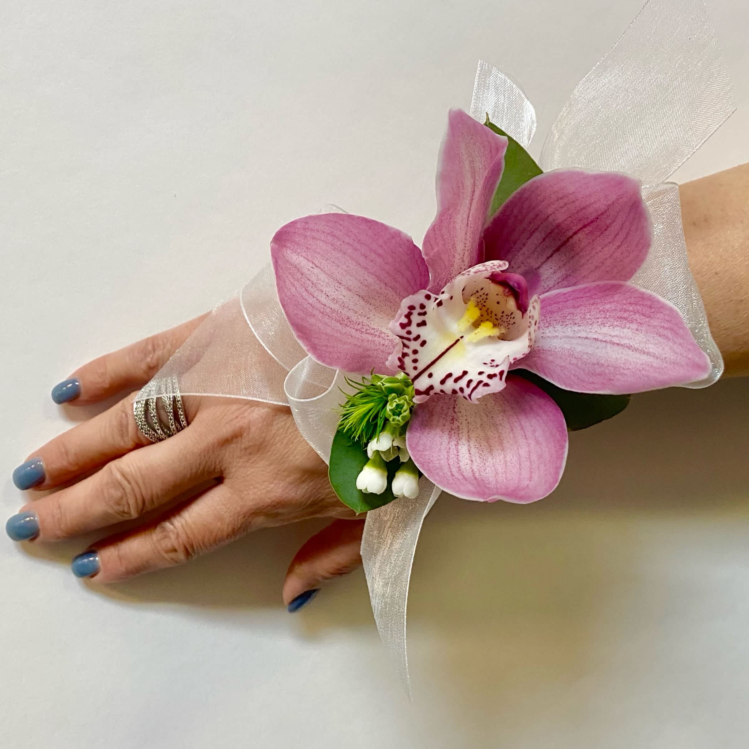 Pink orchid corsage with white ribbon on a wrist