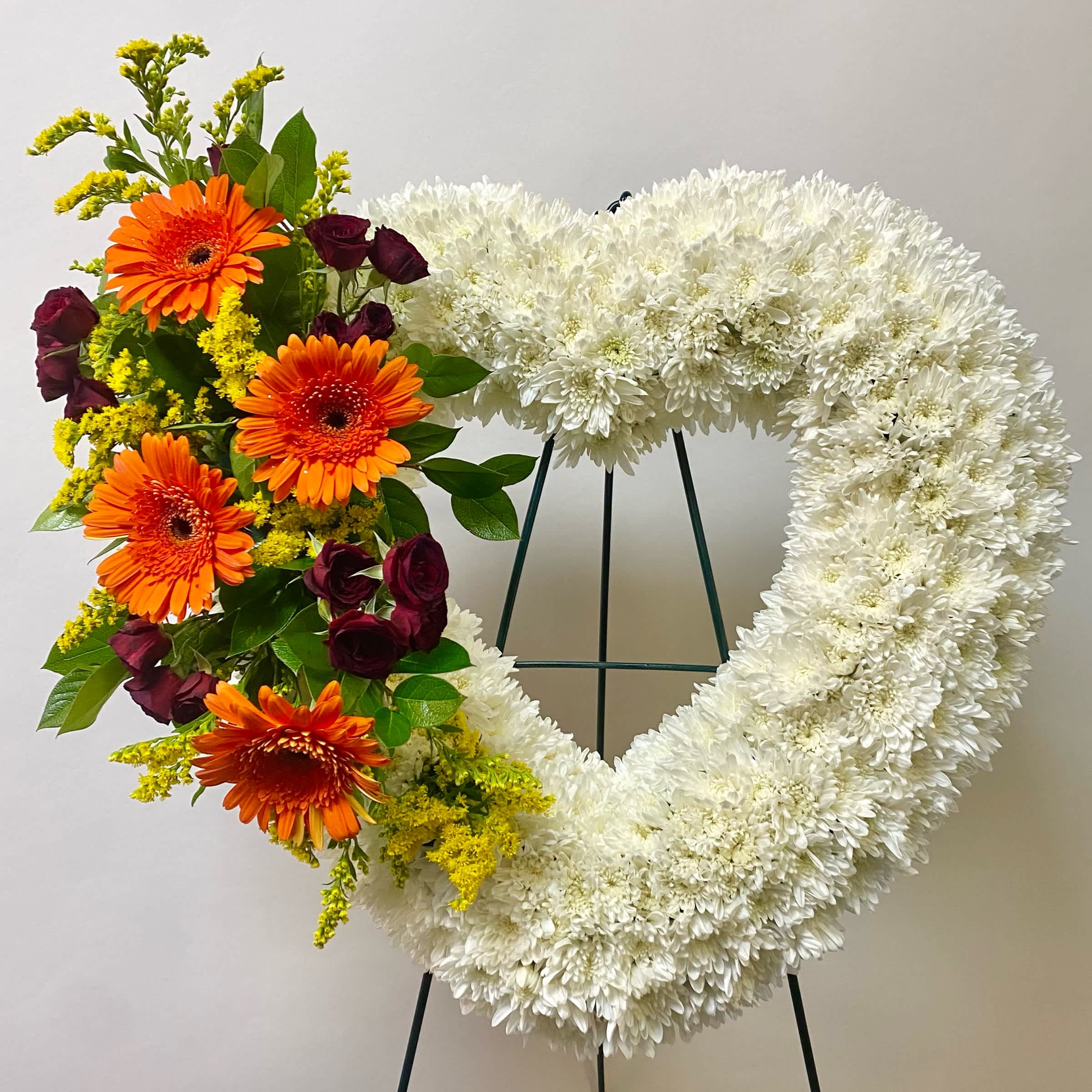 Heart-shaped floral wreath with white chrysanthemums and orange gerberas