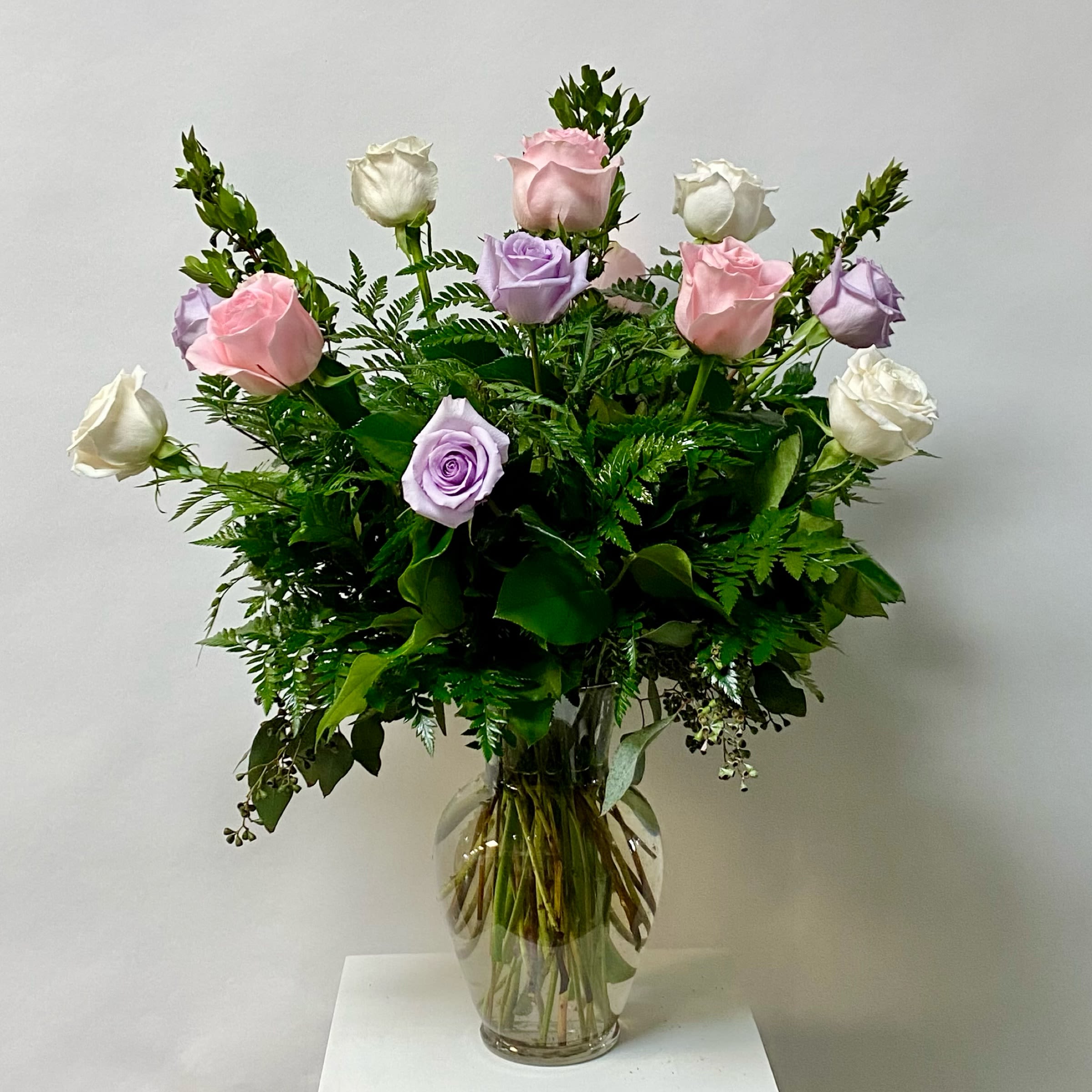 Bouquet of pink, lavender, and white roses in a clear glass vase