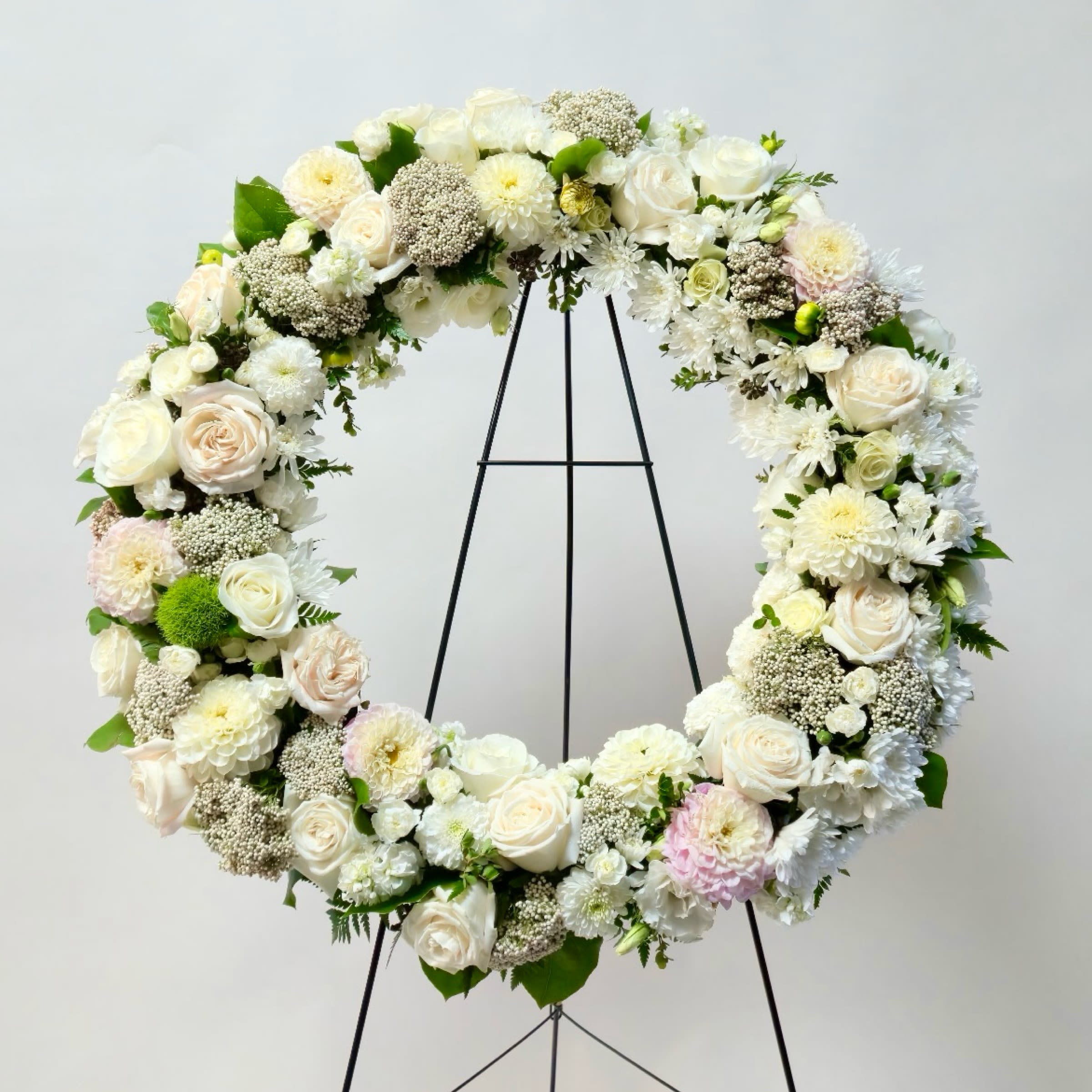 Large white floral wreath on a black stand