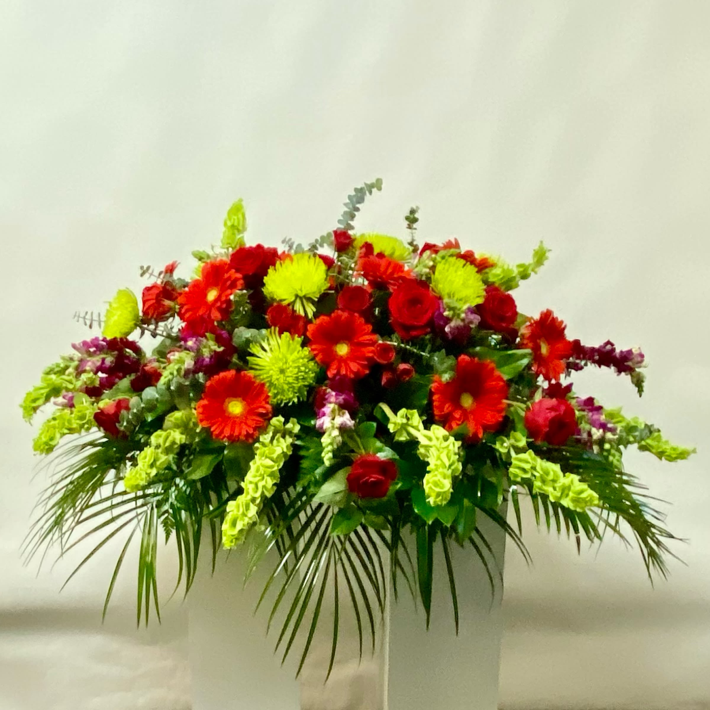 Large red and neon green floral arrangement in a white container