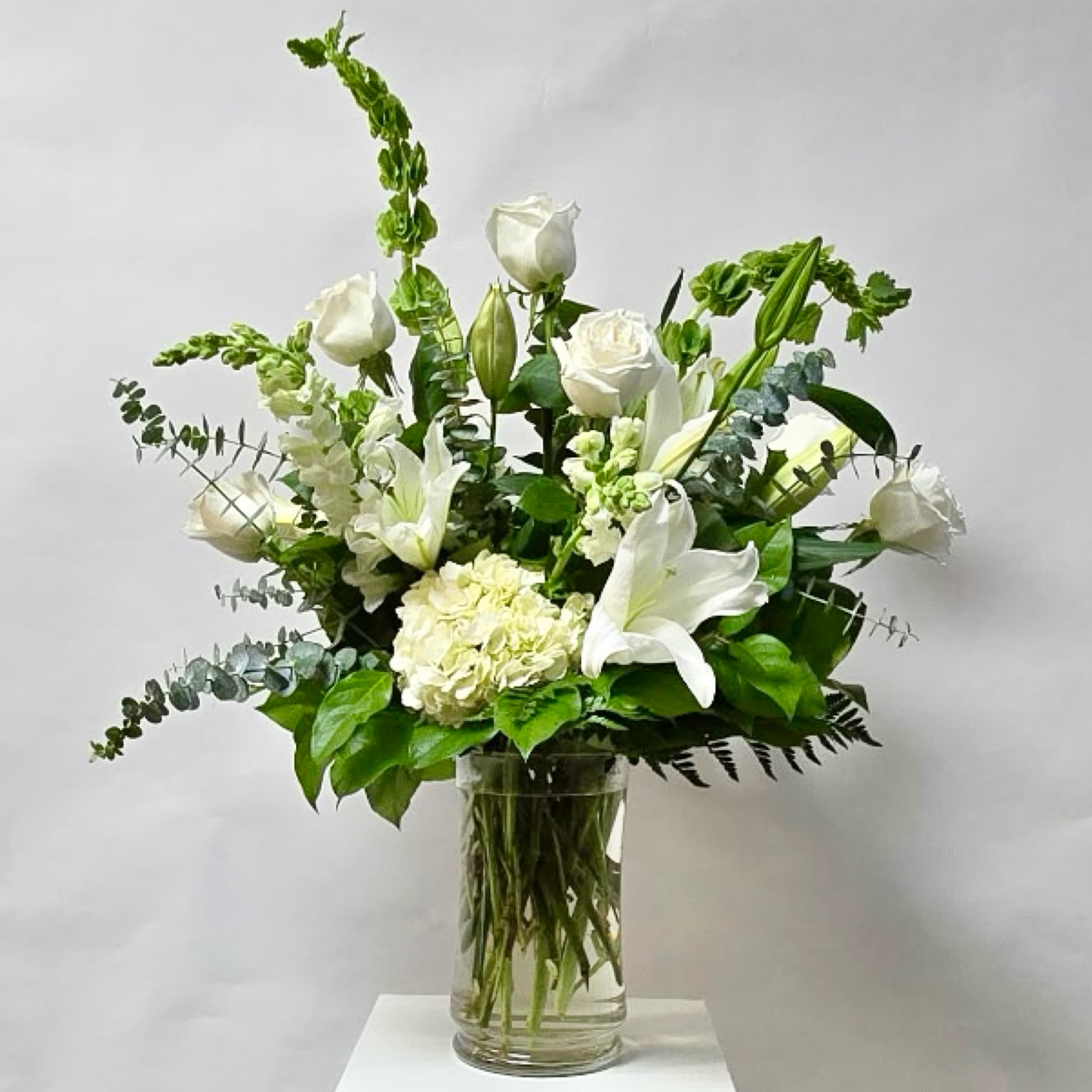 White roses and lilies arranged in a clear glass vase
