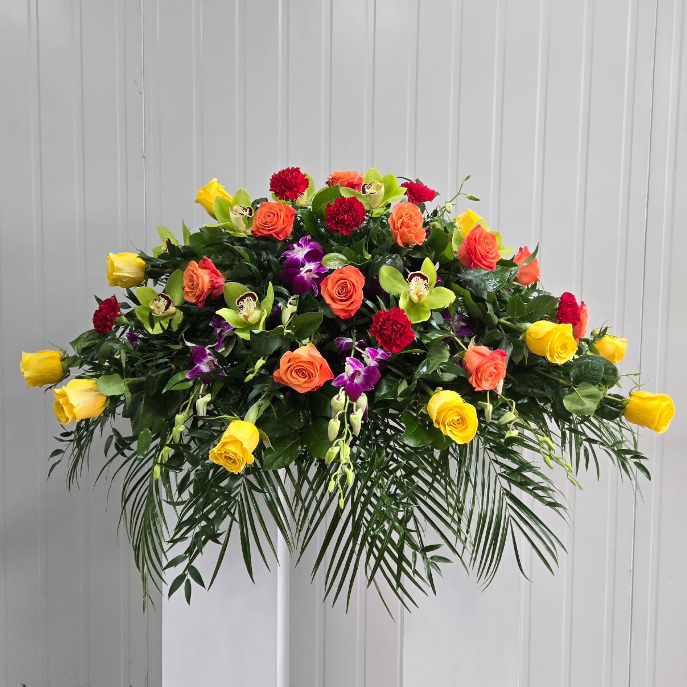 Sunset Tribute Casket Spray - This Casket Spray Includes Green Cymbidium Orchid Blooms, Purple Dendrobium Orchids, Yellow Roses, Orange Roses and Red Carnations. Or as Similar as Possible. 
