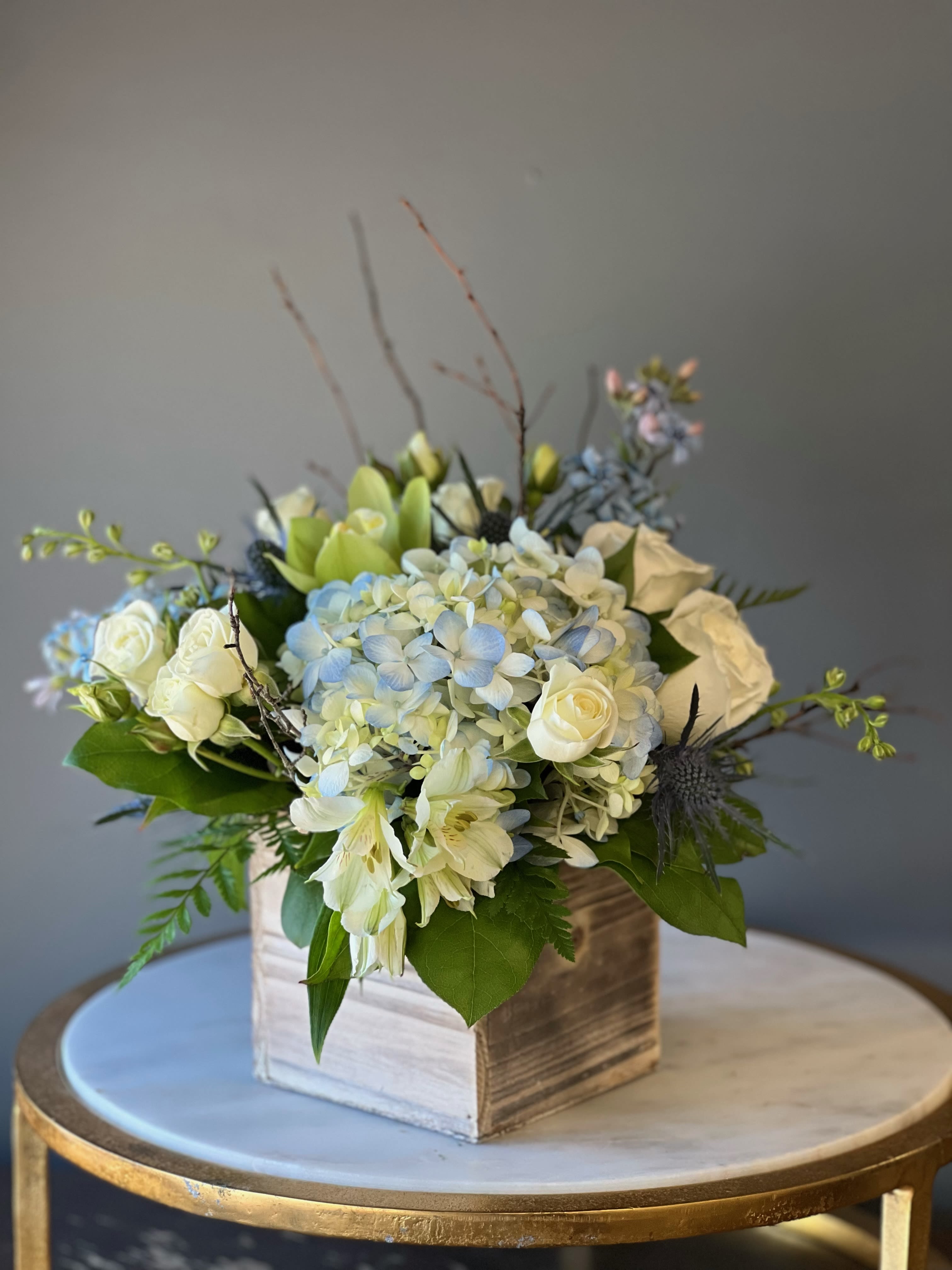 White and pale blue floral arrangement in a wooden box