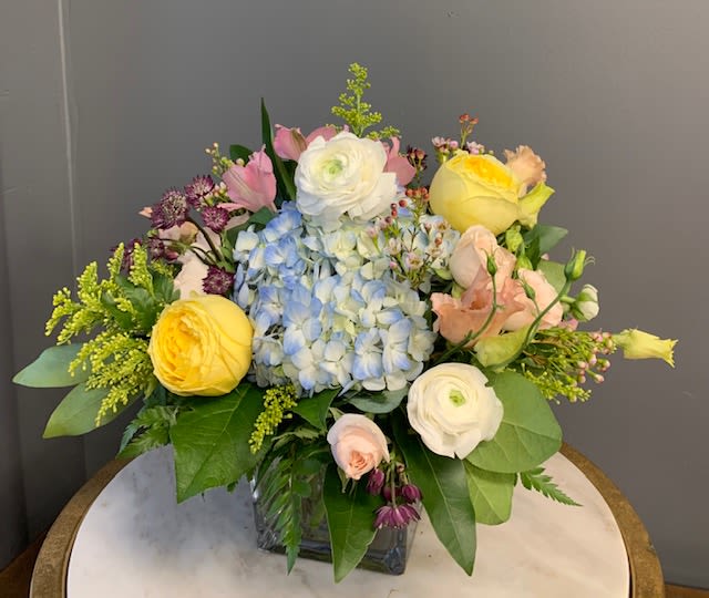 Mixed bouquet with hydrangea, roses, and ranunculus in a glass vase