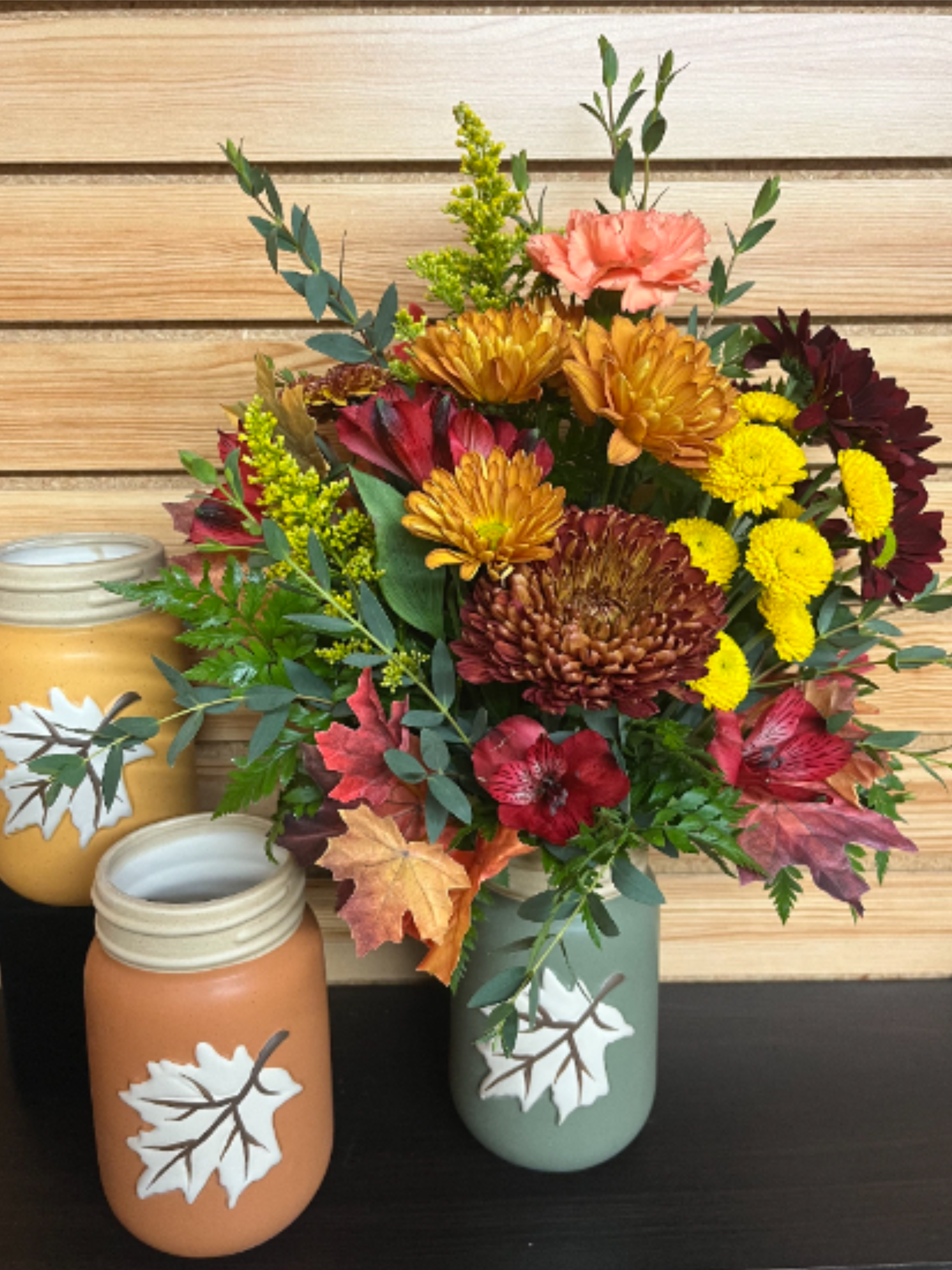 Autumn bouquet in a painted mason jar with yellow, burgundy, and peach flowers