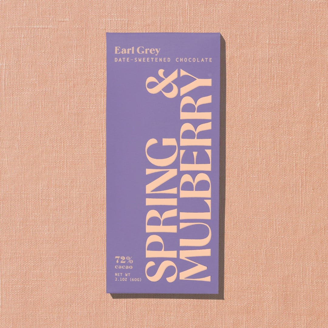 Purple Earl Grey chocolate bar package on a peach textured background