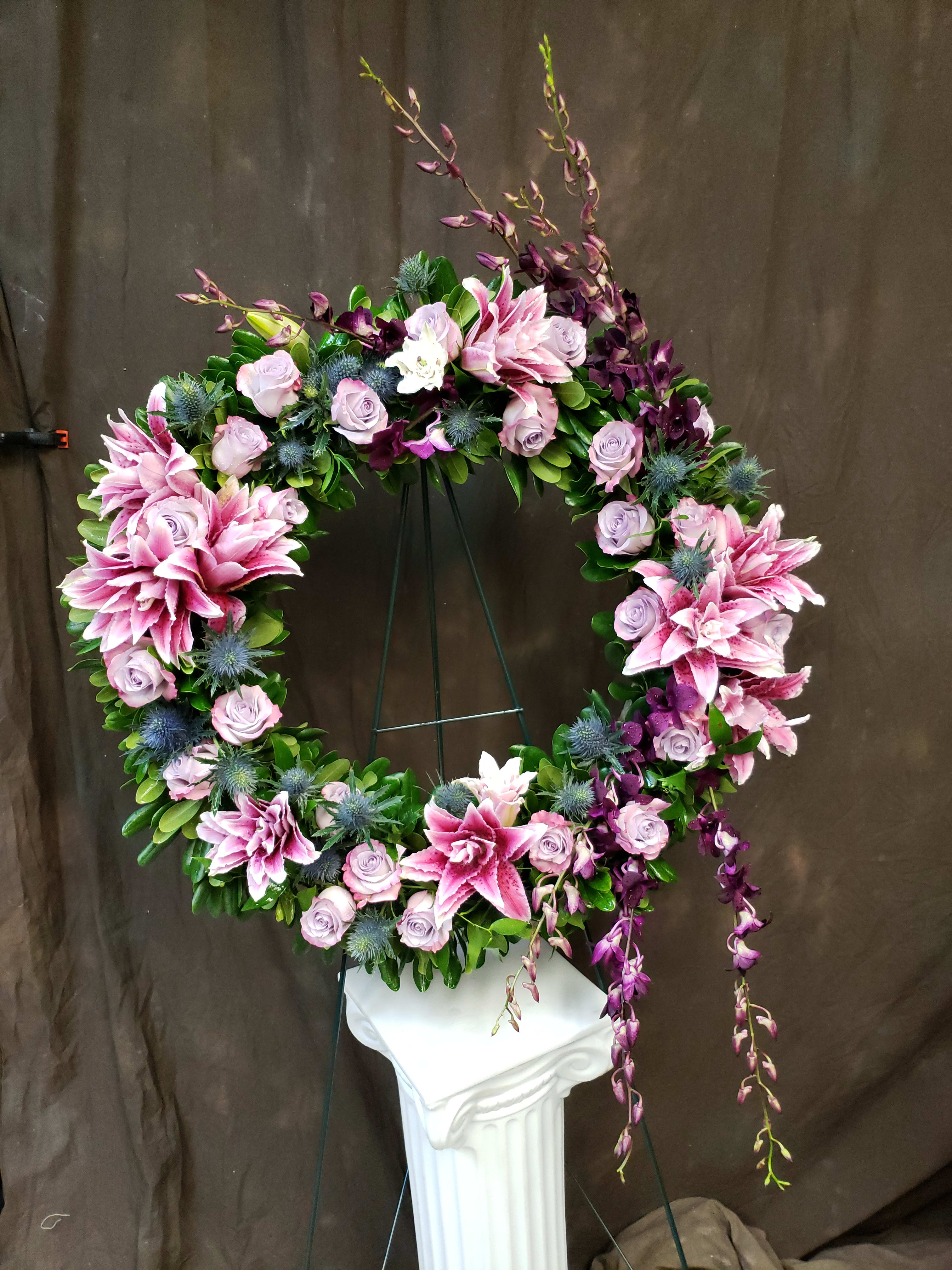 Circular floral wreath with pink lilies and lavender roses on a stand
