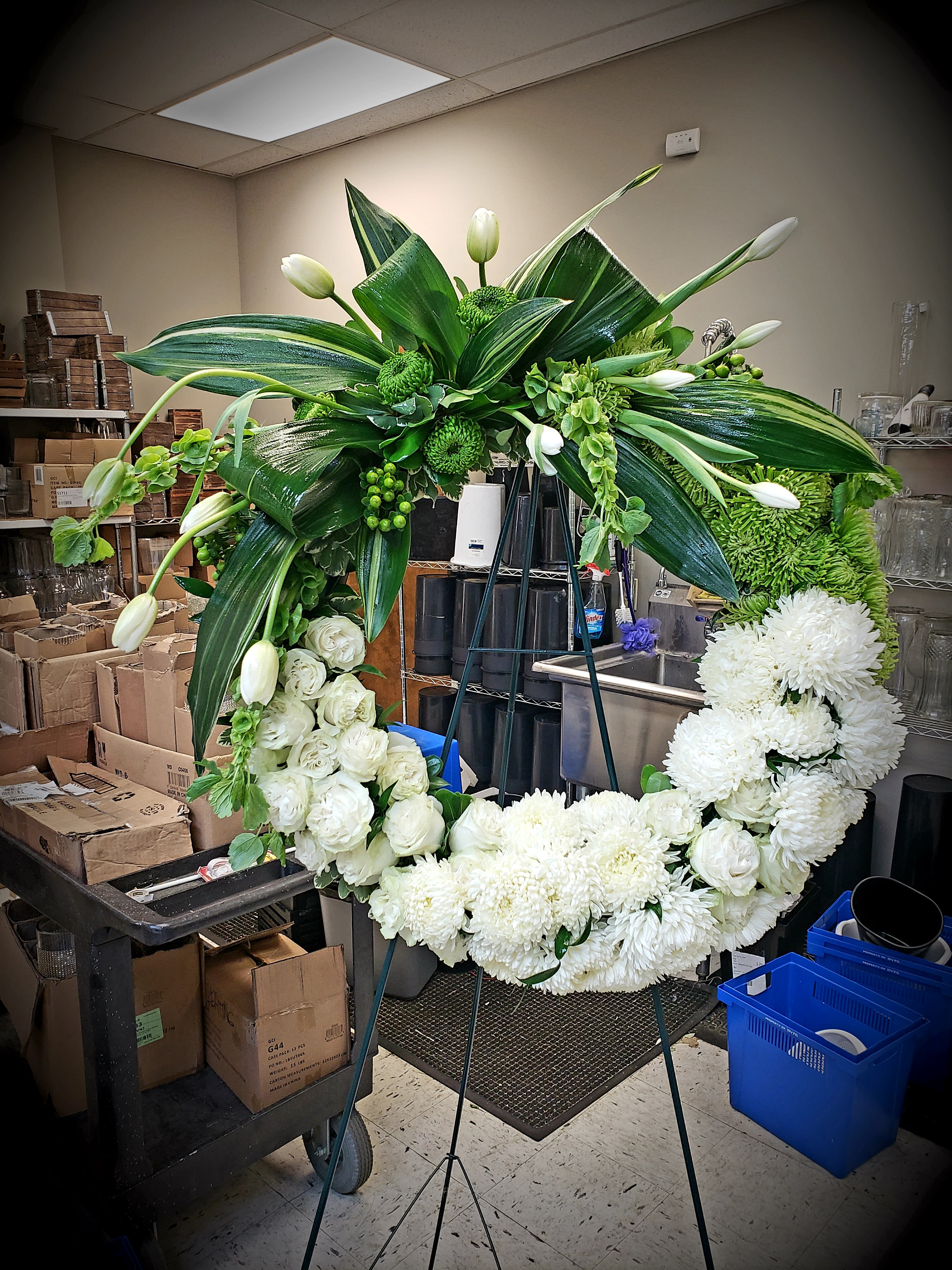 Large white floral wreath on an easel with green foliage and tulips
