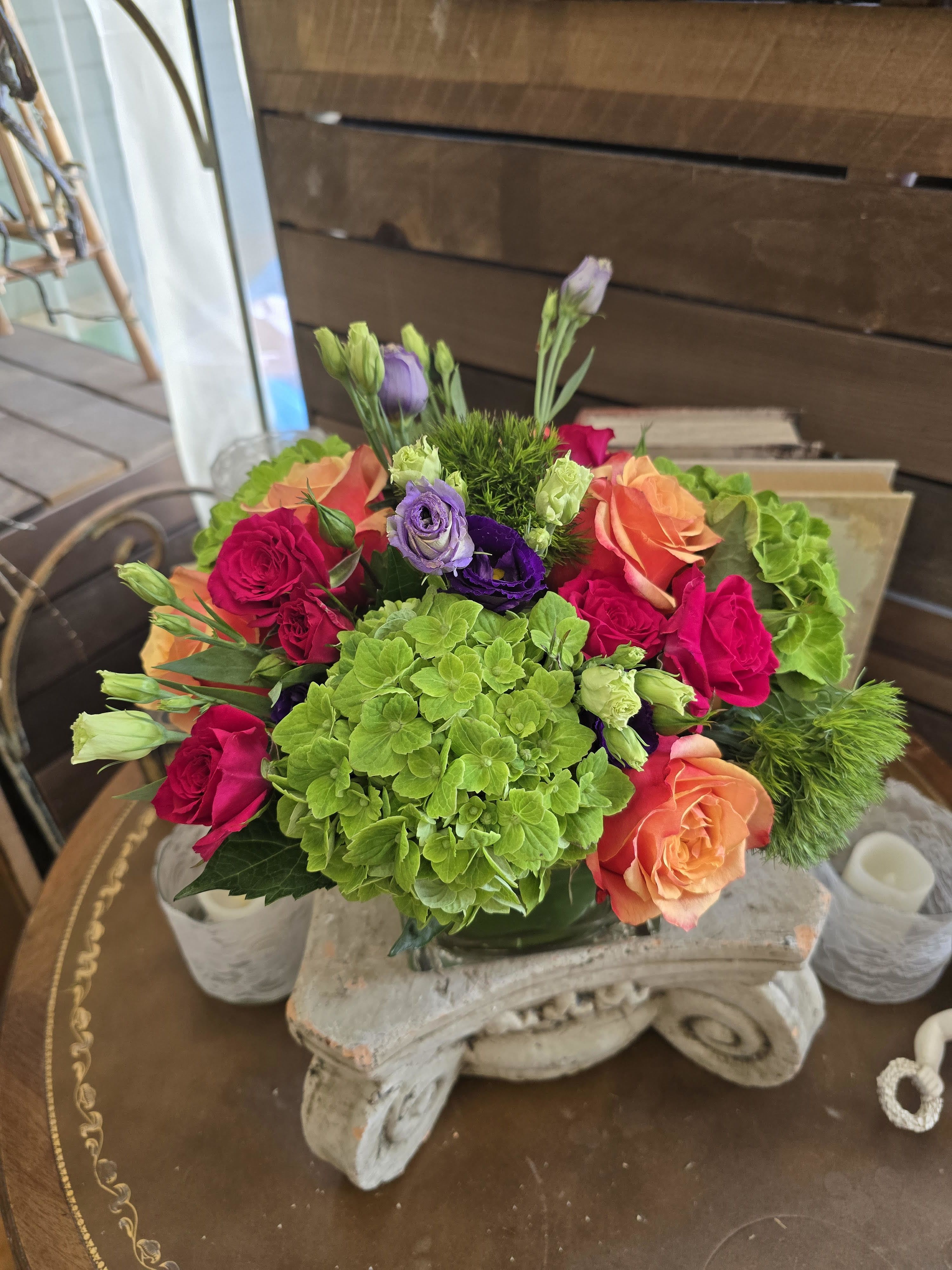 Bouquet of pink, orange, purple, and green flowers in a glass vase