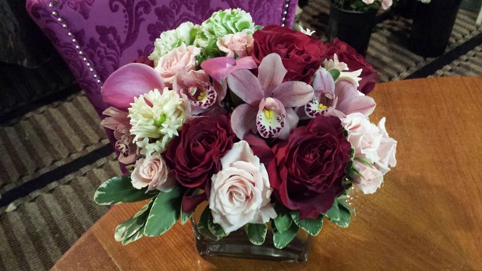Bouquet of pink and burgundy flowers in a square glass vase