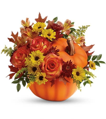 Fall floral arrangement in a pumpkin container with roses and daisies