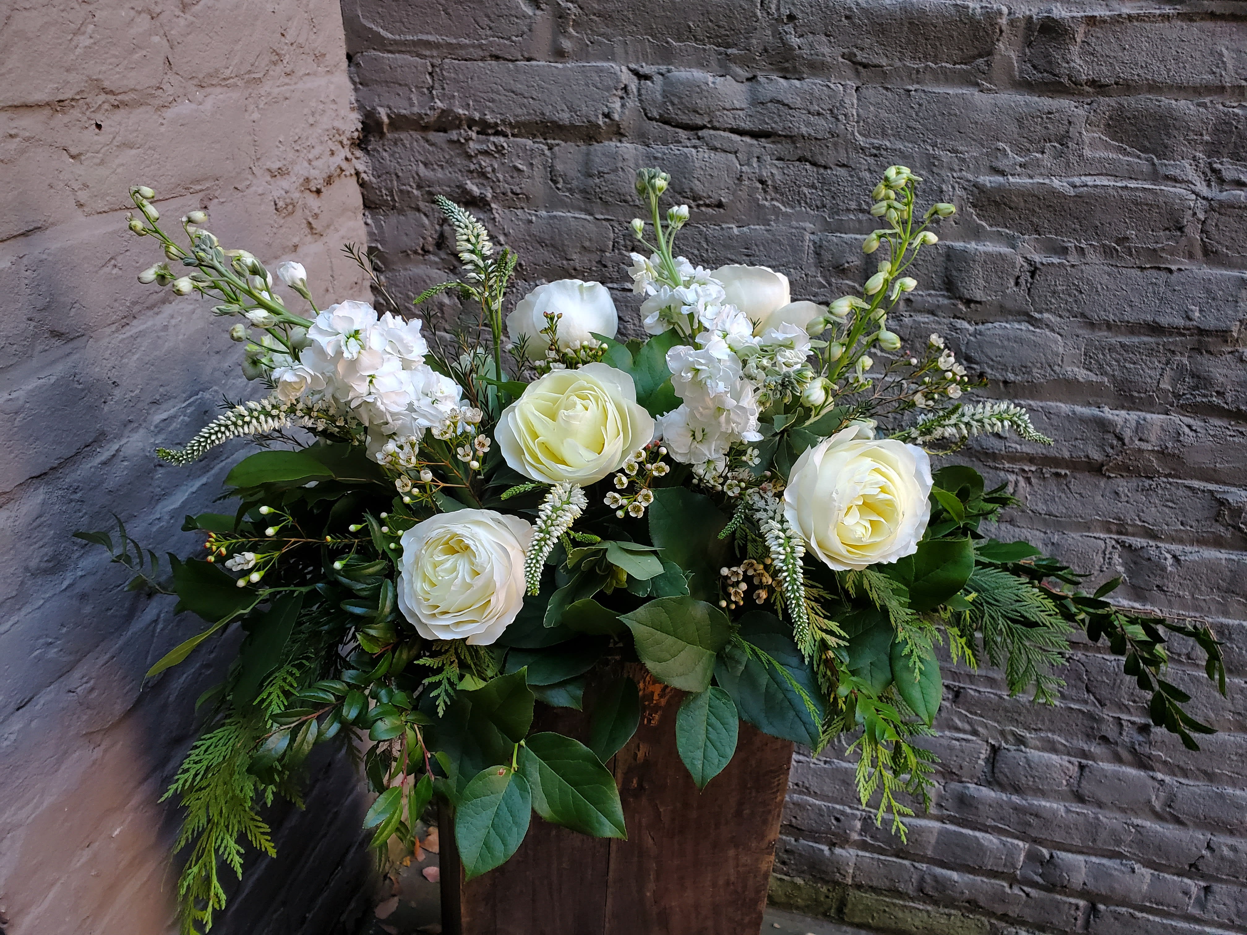 White roses and white blooms in a rustic wooden container