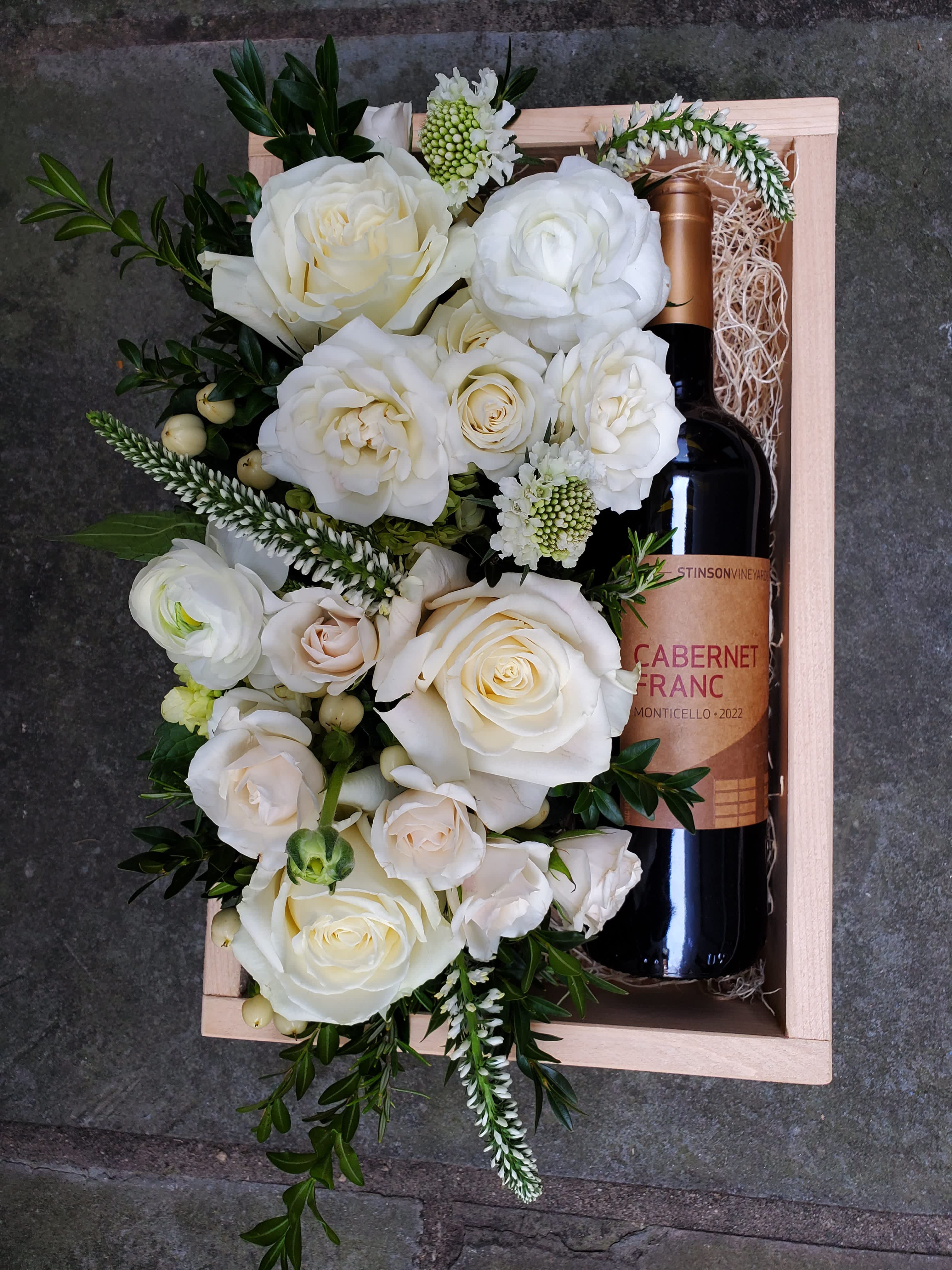 Cabernet Franc Gift Box - A beautiful wooden gift box, locally hand-crafted from reclaimed wood. A bottle of Stinson Vineyard's Cabarnet Franc rests on a bed of Spanish moss, alongside a beautiful bed of flowers in the pavé style. You may specify a color for this arrangement if desired.  Wine Description: Cabernet Franc has earned an international reputation for quality in Virginia and Stinson Vineyards has mastered this wine.  Medium-bodied with spicy tannins, dried floral aromatics and flavors of black cherry and white peppercorn make it an ideal red enjoyed while nestled by the fireplace.  Before placing your order, please ensure that the recipient is above 21 years of age and will be home to receive the delivery, as ABC regulation requires that we check photo ID upon delivery. If no one is present at the delivery site, delivery cannot be completed.  Box measures 8.5x11.5".