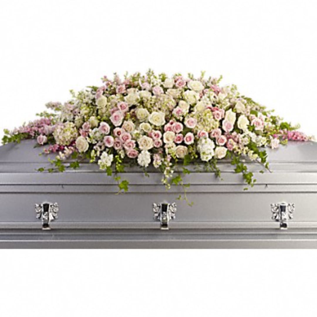 Pastel pink and white floral spray on a silver casket