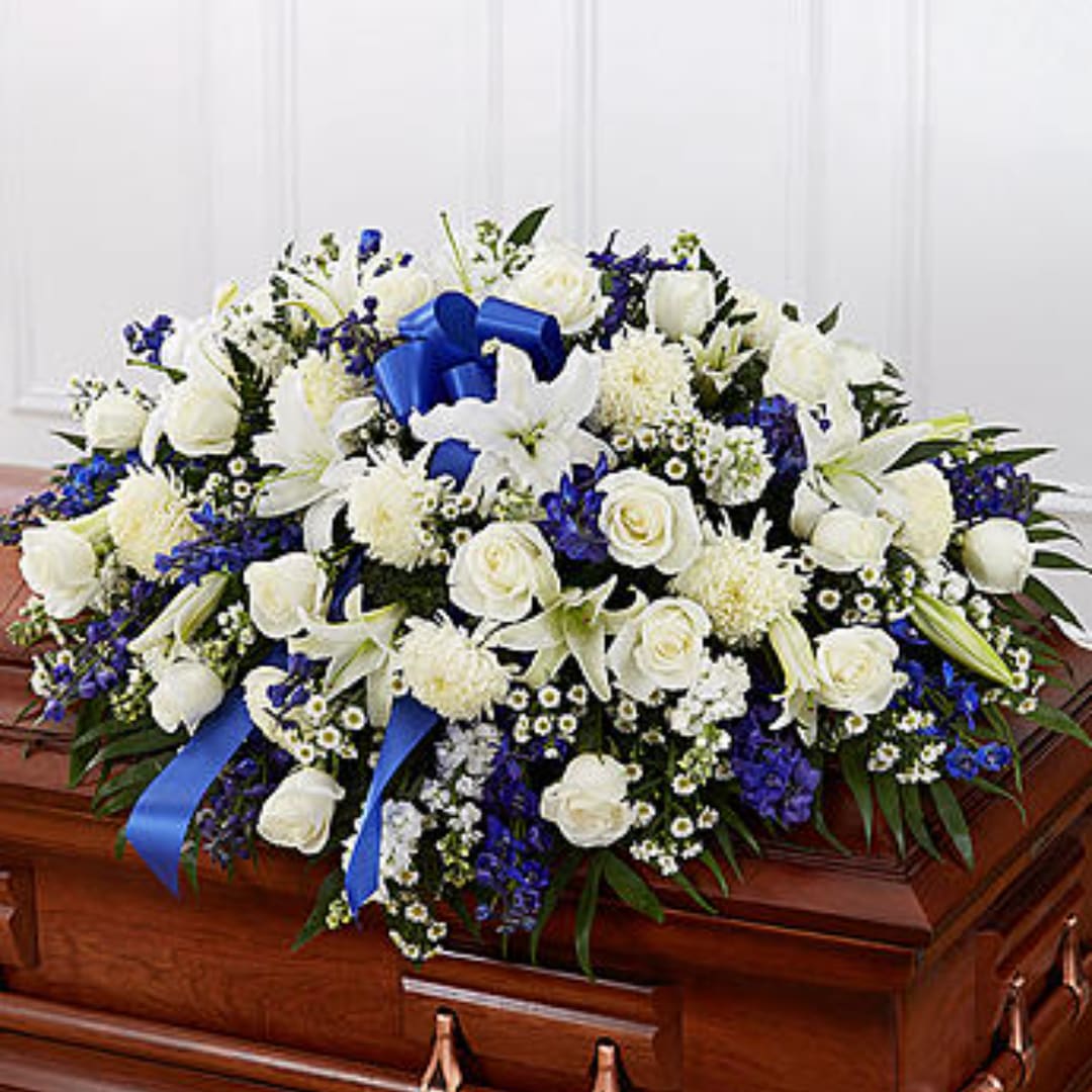 White and blue floral arrangement on a wooden casket