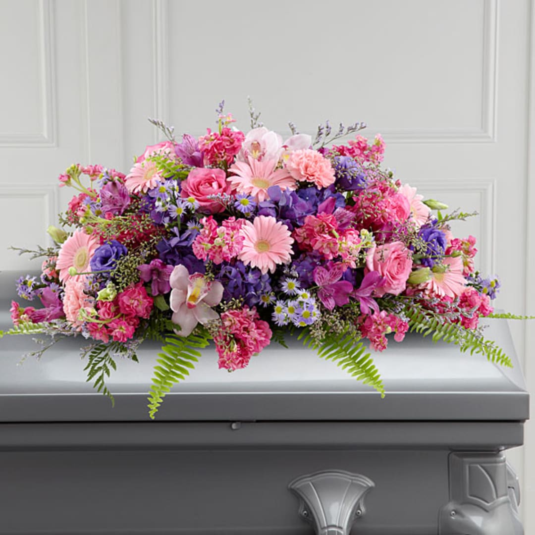 Pink and purple mixed flower arrangement on a gray casket