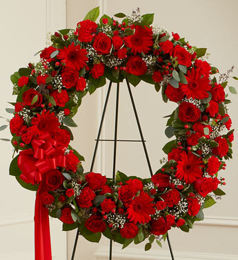Red floral wreath on a black stand with a ribbon bow
