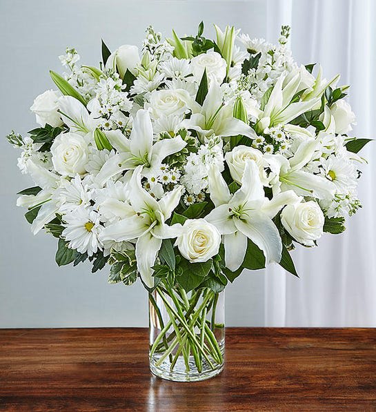 White lilies and roses arranged in a clear glass vase
